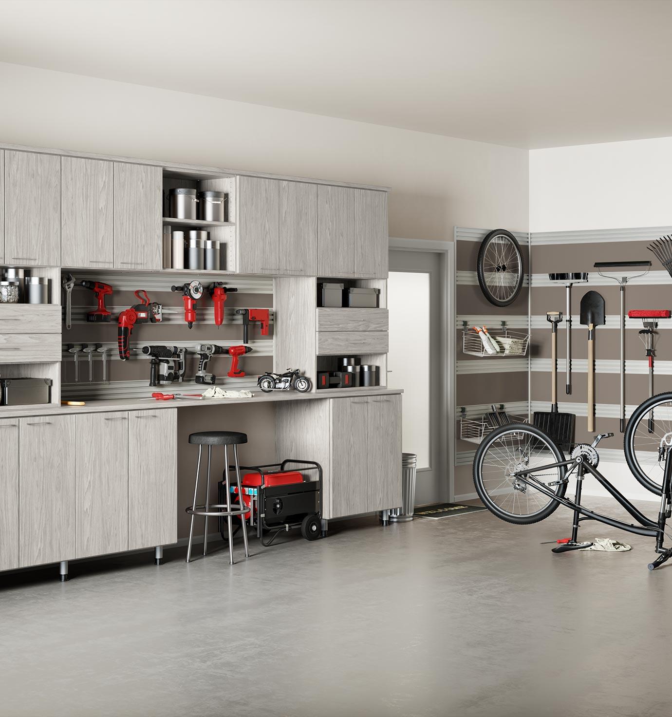 View of a garage transformed into a workshop with wooden cabinets, red power tools, a generator, a stool, and a bike mounted on a repair stand. Side shelves hold additional tools and supplies.