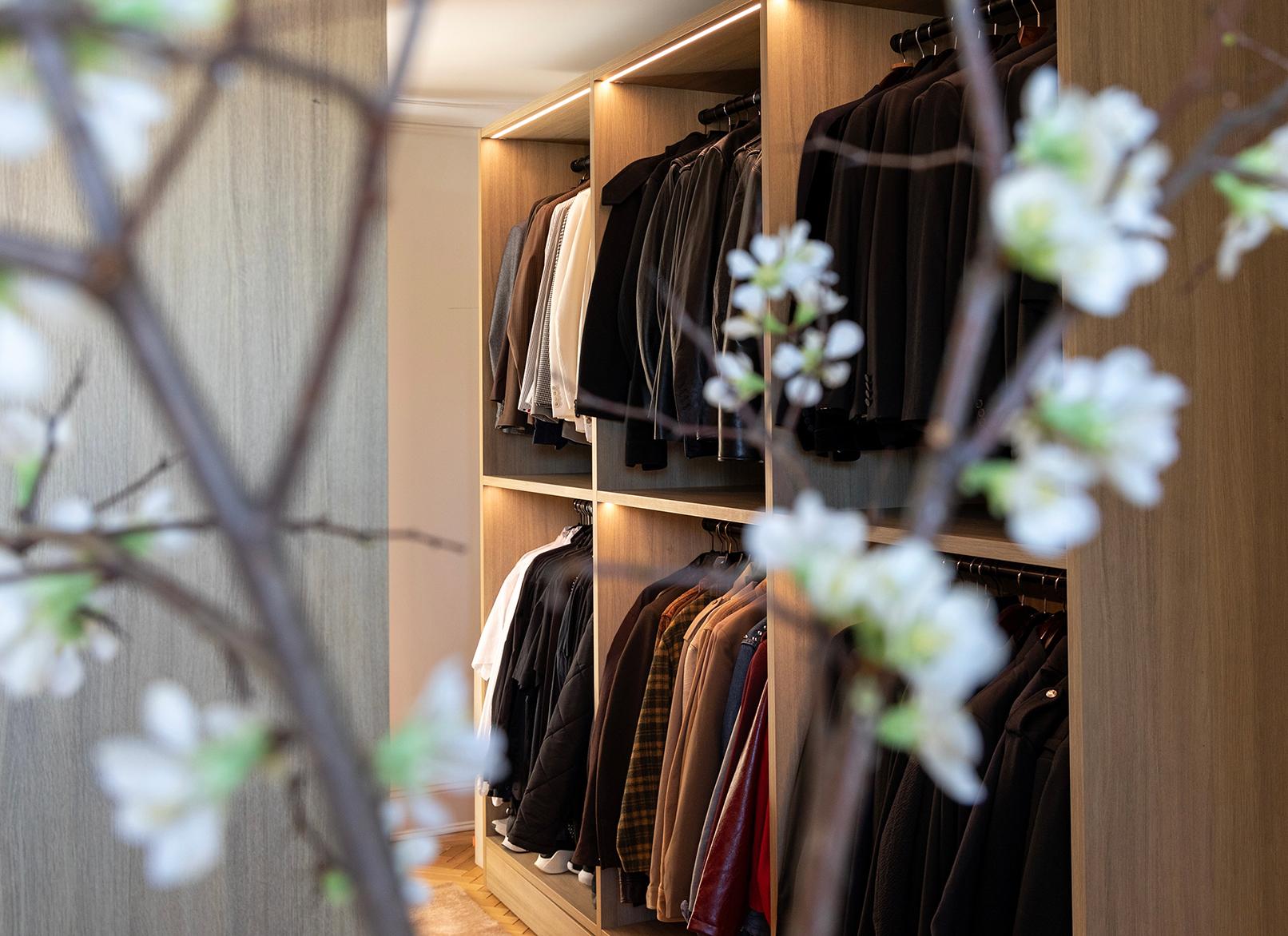 Walk in closet with custom open wardrobe storage and lighting by Jeremiah Brent and California Closets