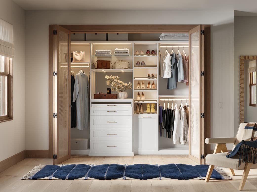 Reach in closet customized LED lighting, with open shelving, long and short hanging wardrobe bars and closet organizers by California Closets