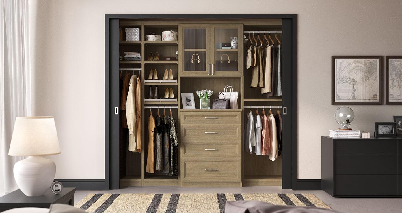Custom reach in closet with built in dresser, glass door cabinets in walnut finish by California Closets