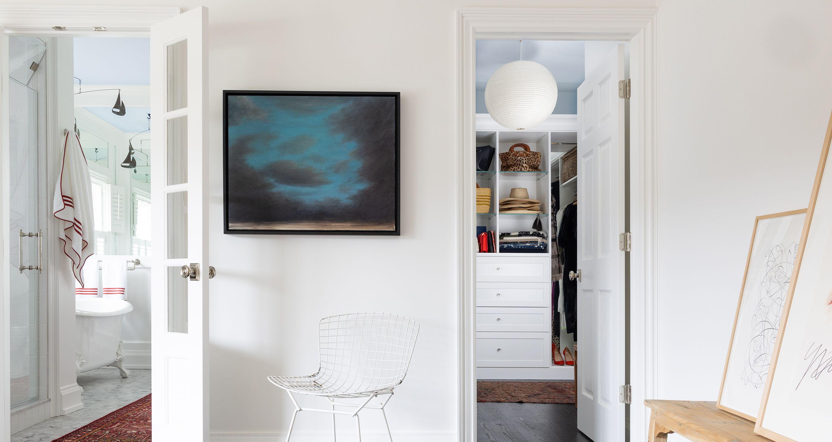 Light and airy walk in closet designed with custom drawers, open shelving, and hanging clothes racks by California Closets