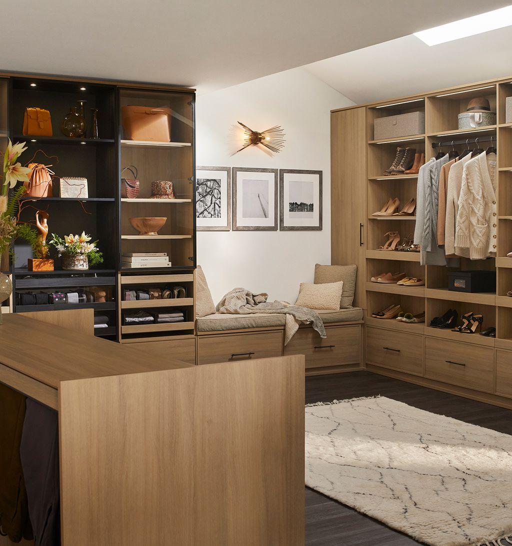 Walk in closet designed for his and hers wardrobes with bench and island by California Closets