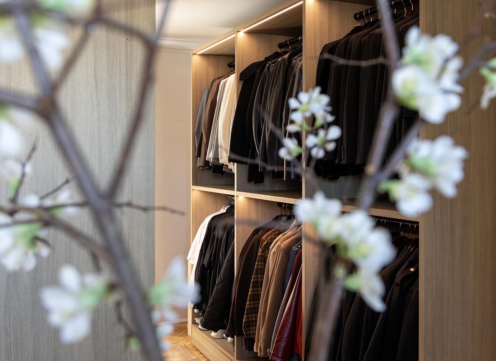 Walk in closet with hanging poles, lighting, and open wardrobe shelves by Jeremiah Brent and California Closets
