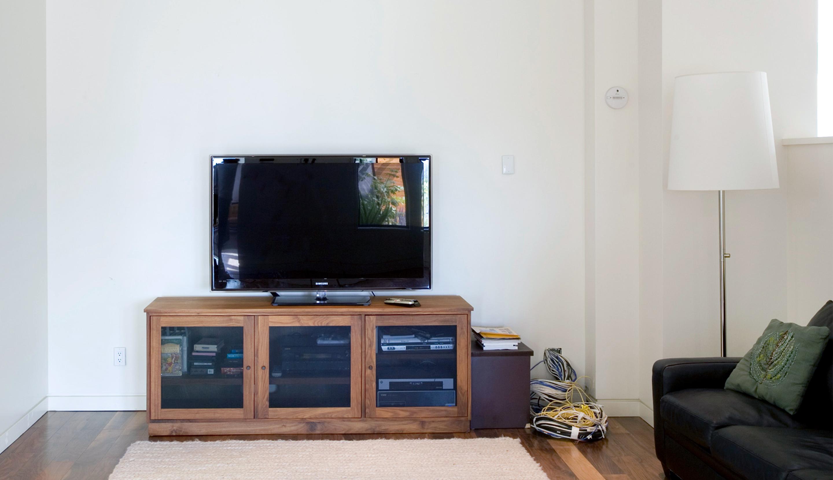 Living room with outdated TV stand and no storage before entertainment center installation by California Closets