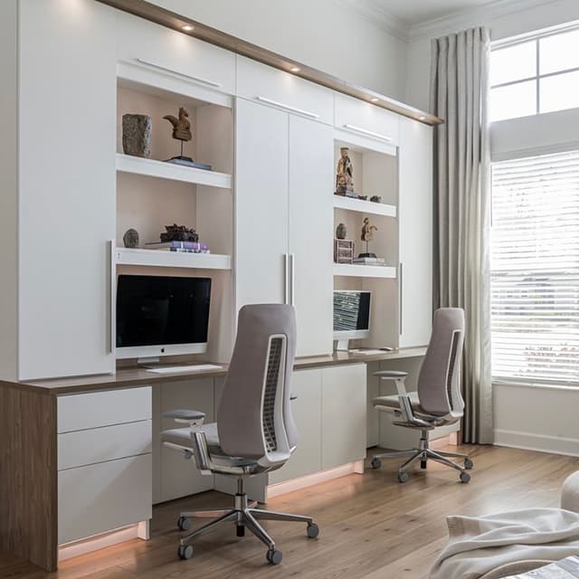 Home office workspace designed with custom shelving and two work desks storage drawers by California Closets